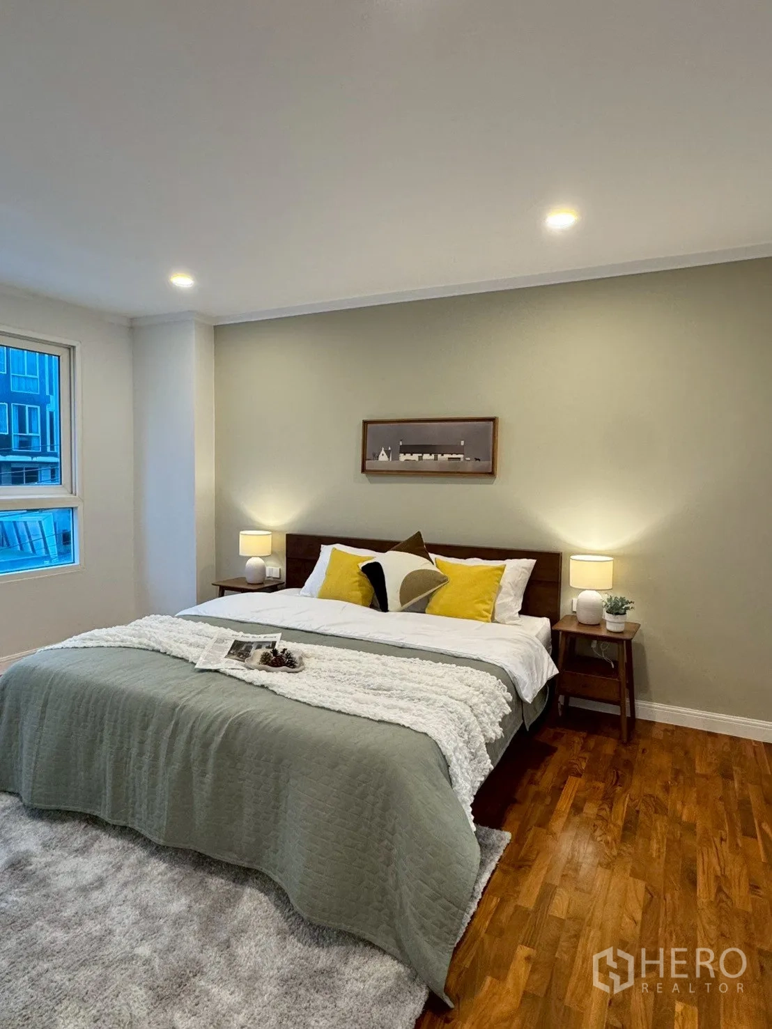 Condominium for sale in Watthana, Bangkok - Cozy bedroom with double bed, side tables and lamps, large window, and wood flooring.