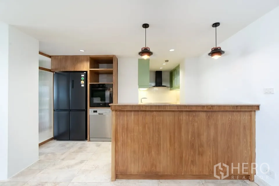 公寓 for rent in Watthana, Bangkok - 厨房区设木质吧台、黑色冰箱、烤箱和洗碗机。