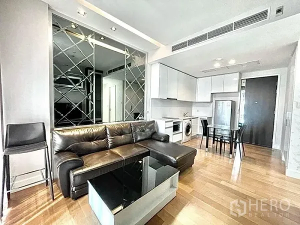 Condominium for rent in Chatuchak, Bangkok - Open living-dining area with leather sofa, mirrored wall and full kitchen.