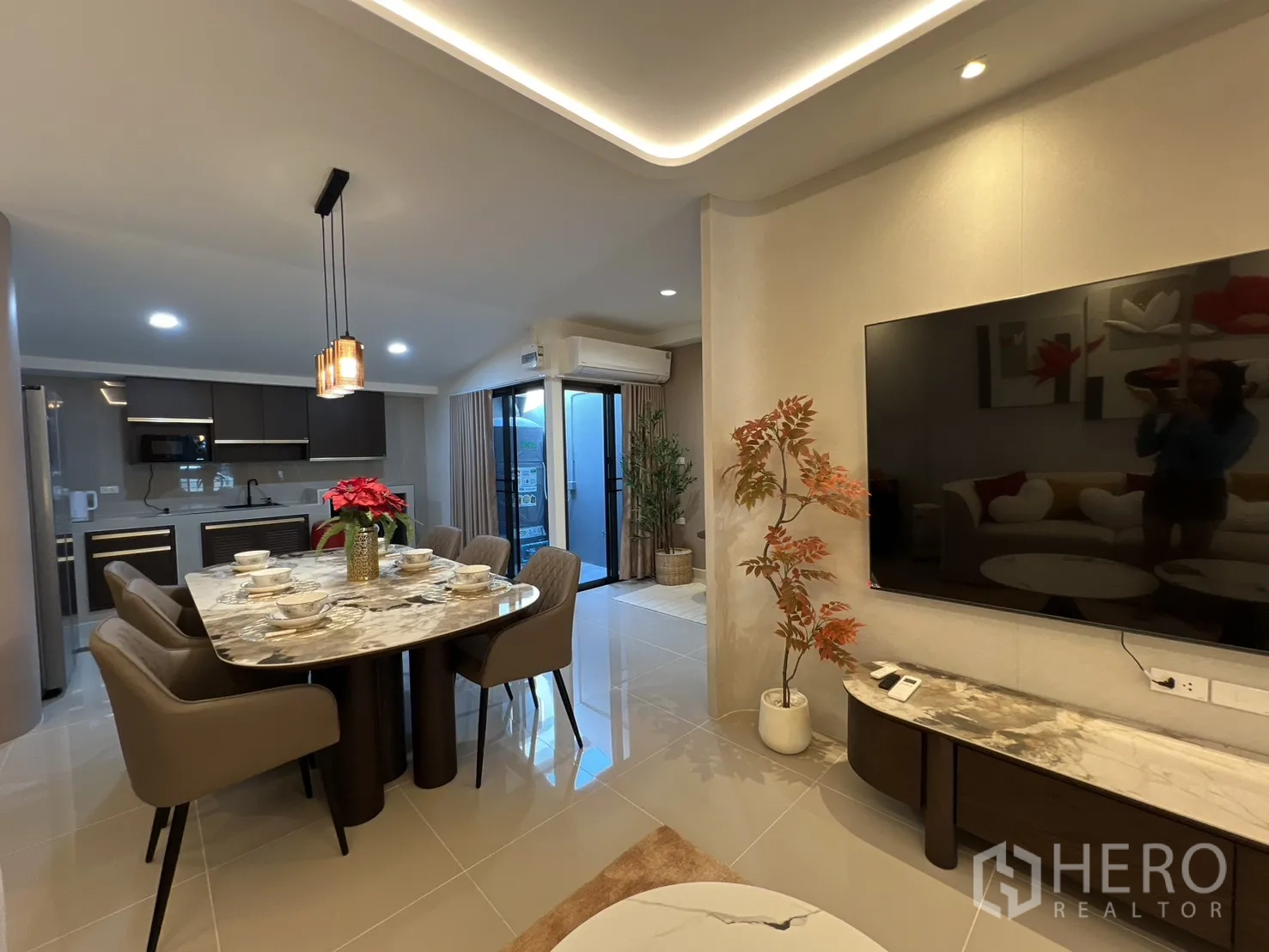 Townhouse for rent in Bang Phli, Samut Prakan - Open-plan living, dining and kitchen with a marble dining table and a large TV wall.