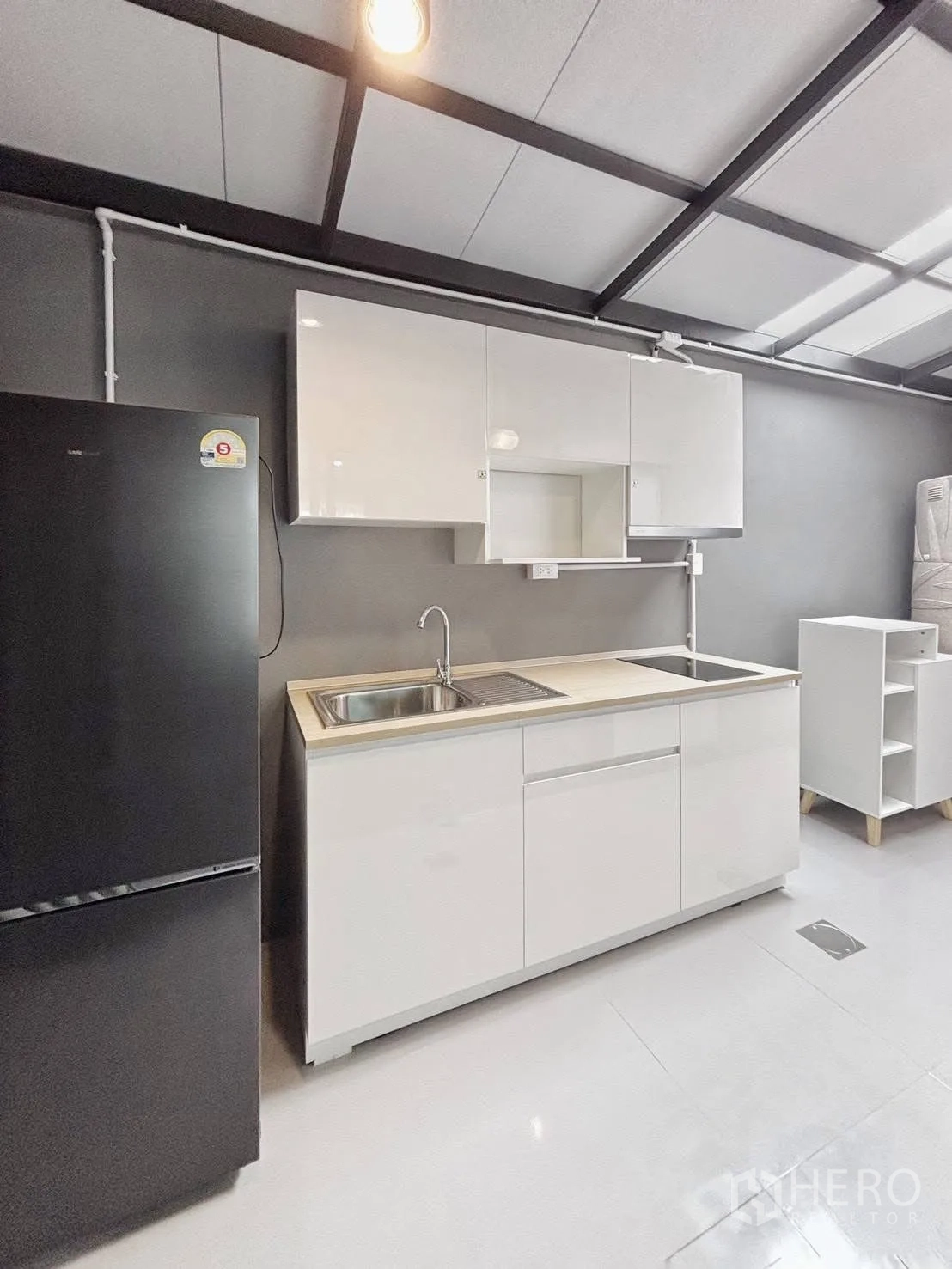 联排别墅 for rent in Bang Phli, Samut Prakan - 一体化厨房，白色橱柜、水槽、电磁炉与黑色冰箱，外露梁顶