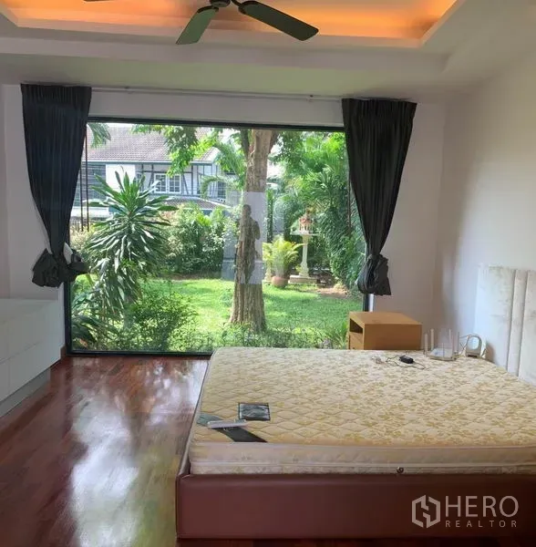 Detached House for rent in Din Daeng, Bangkok - Ground-floor bedroom with floor-to-ceiling window overlooking a green private garden.