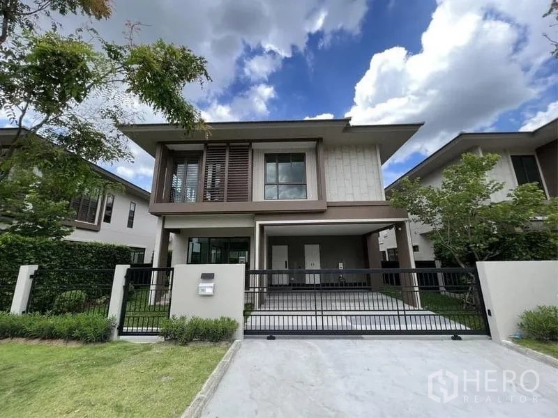 บ้าน ขายในBang Kapi, Bangkok - ด้านหน้าบ้านพร้อมทางเข้ารถกว้าง ประตูรั้วสีดำ และจัดสวนเรียบร้อย