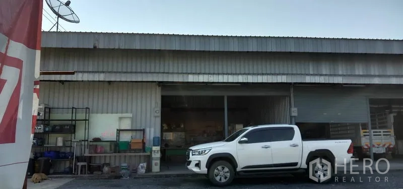 คลังสินค้า ให้เช่าในKhlong Sam Wa, Bangkok - หน้าโกดังหนึ่งยูนิต ประตูม้วนเปิดเห็นชั้นเก็บของด้านใน มีรถกระบะจอดหน้าทางเข้า