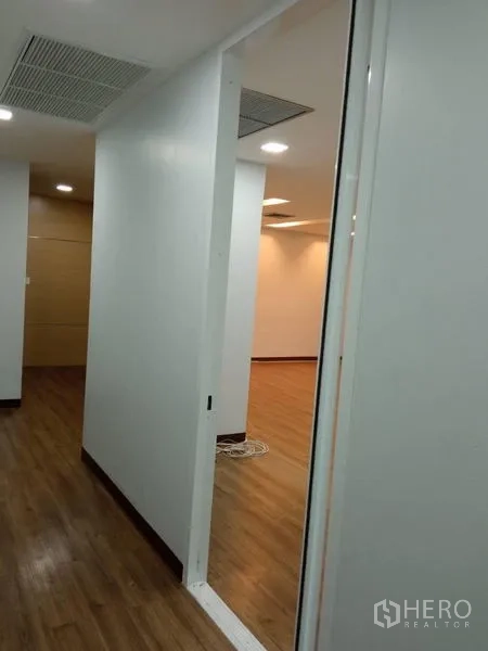 办公空间 出租在Huai Khwang, Bangkok - 室内走廊，白色隔墙、木地板与天花空调通风口，通向主办公区。