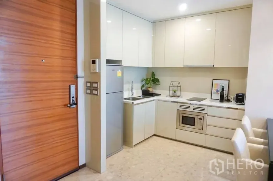 คอนโด ให้เช่าในKhlong Toei, Bangkok - ครัวบิลท์อินโทนขาว ตู้เก็บของเงา ตู้เย็น เตาไฟฟ้า และที่นั่งทานอาหาร คอนโดกรุงเทพ
