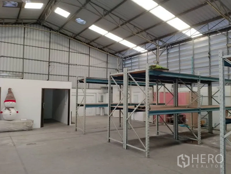 Warehouse for rent in Huai Khwang, Bangkok - Open warehouse area with office entrance, metal racks and insulated gable roof.