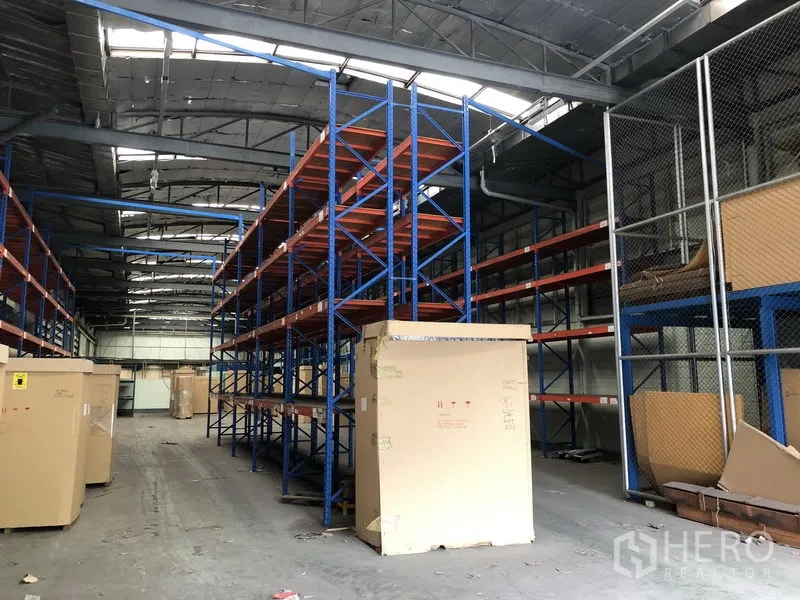 Factory for rent in Lam Luk Ka, Pathum Thani - Aisle between long storage racks under a metal roof, highlighting storage capacity.