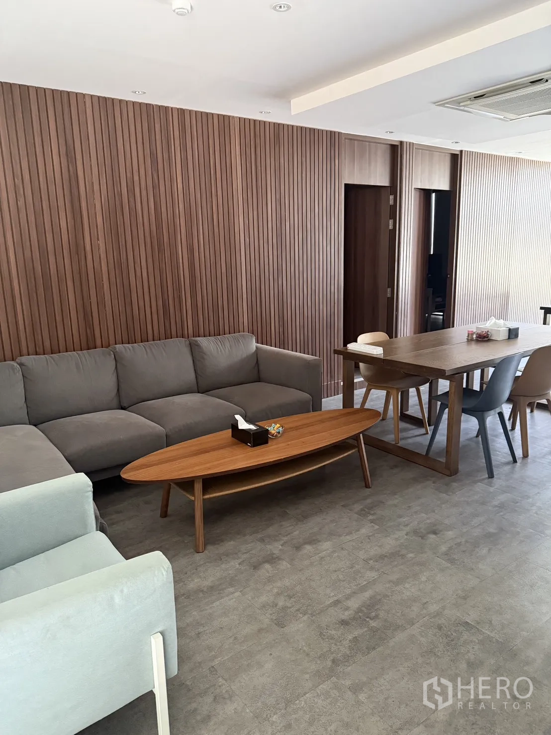 家庭办公室 for rent in Watthana, Bangkok - 客厅休息区配灰色沙发、木质茶几与餐会桌，木饰面墙体。