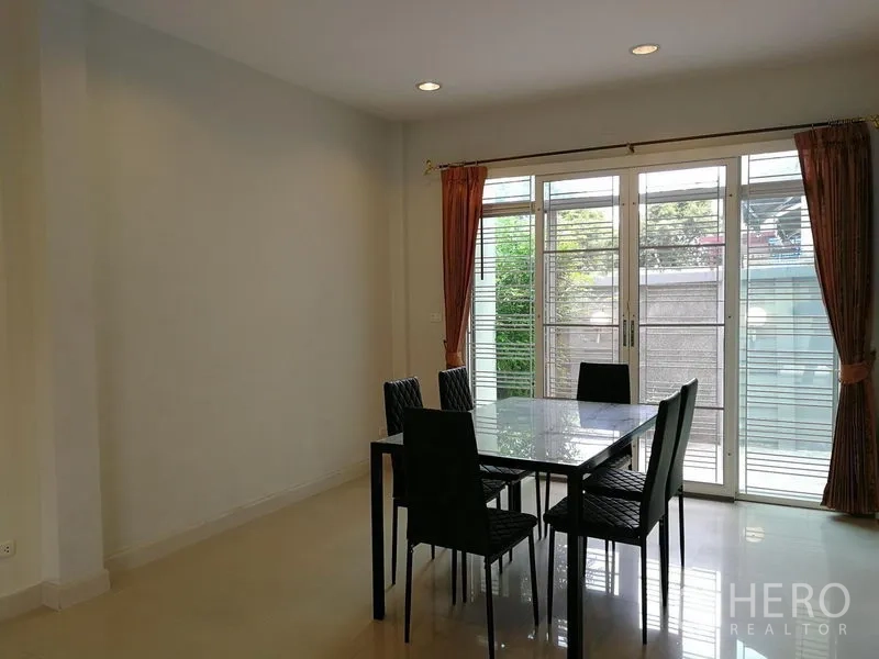 ทาวน์เฮาส์ ให้เช่าในPhasi Charoen, Bangkok - มุมรับประทานอาหารสว่างด้วยโต๊ะกระจก เก้าอี้ และประตูกระจกบานเลื่อนพร้อมผ้าม่าน