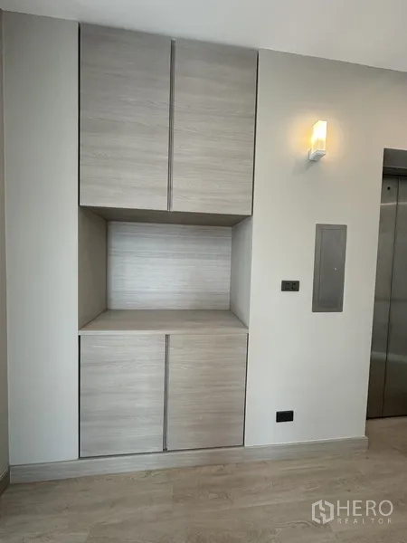 โฮมออฟฟิศ for rent or sale in Suan Luang, Bangkok - ตู้บิลท์อินไม้โทนอ่อนข้างประตูลิฟต์และไฟติดผนัง