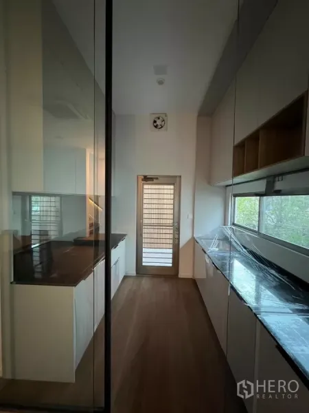 独立式住宅 出租在Saphan Sung, Bangkok - 封闭式长廊厨房，玻璃隔断，长台面并带后门服务区。