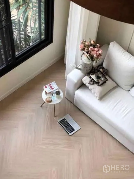 Townhouse for rent - Cozy lounge corner with a white sofa, side table, laptop, and garden view from the window.