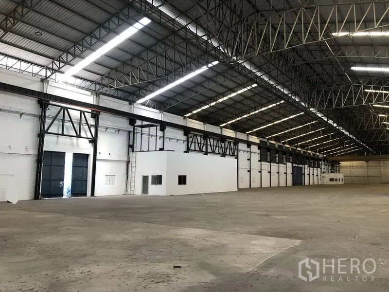 工厂 出租在Mueang Samut Prakan, Samut Prakan - 室内侧视，可见多扇装卸门与一处白色办公室区块。