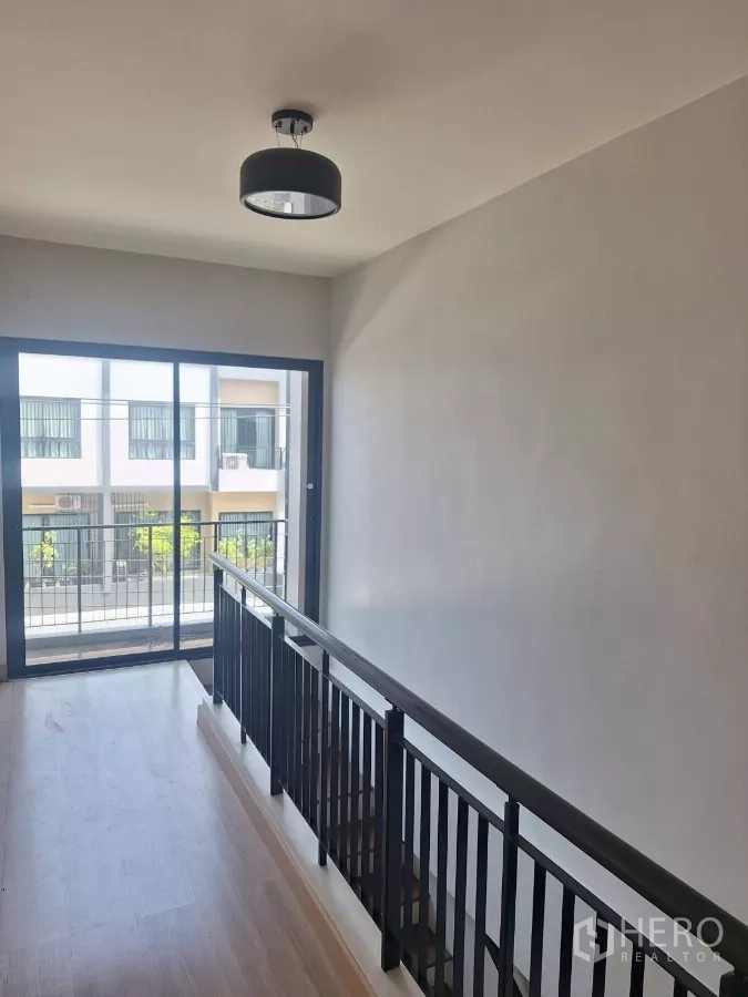 联排别墅 出租在Mueang Samut Prakan, Samut Prakan - 二层过道，推拉门通向阳台，眺望对面联排房。