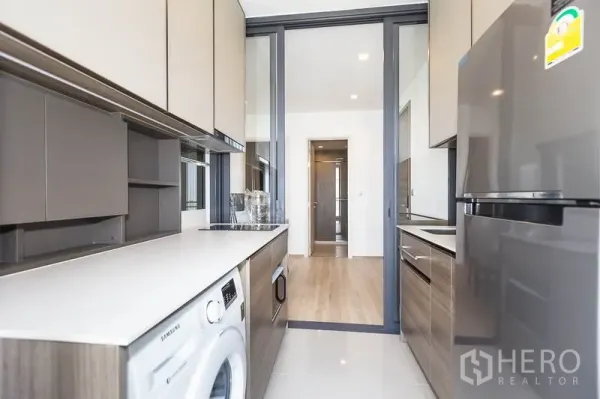 คอนโด ให้เช่าในPhaya Thai, Bangkok - ครัวแบบแกลลีย์ ตู้เก็บของครบ เคาน์เตอร์ยาว ตู้เย็น และเครื่องซักผ้าหลังประตูกระจกบานเลื่อน