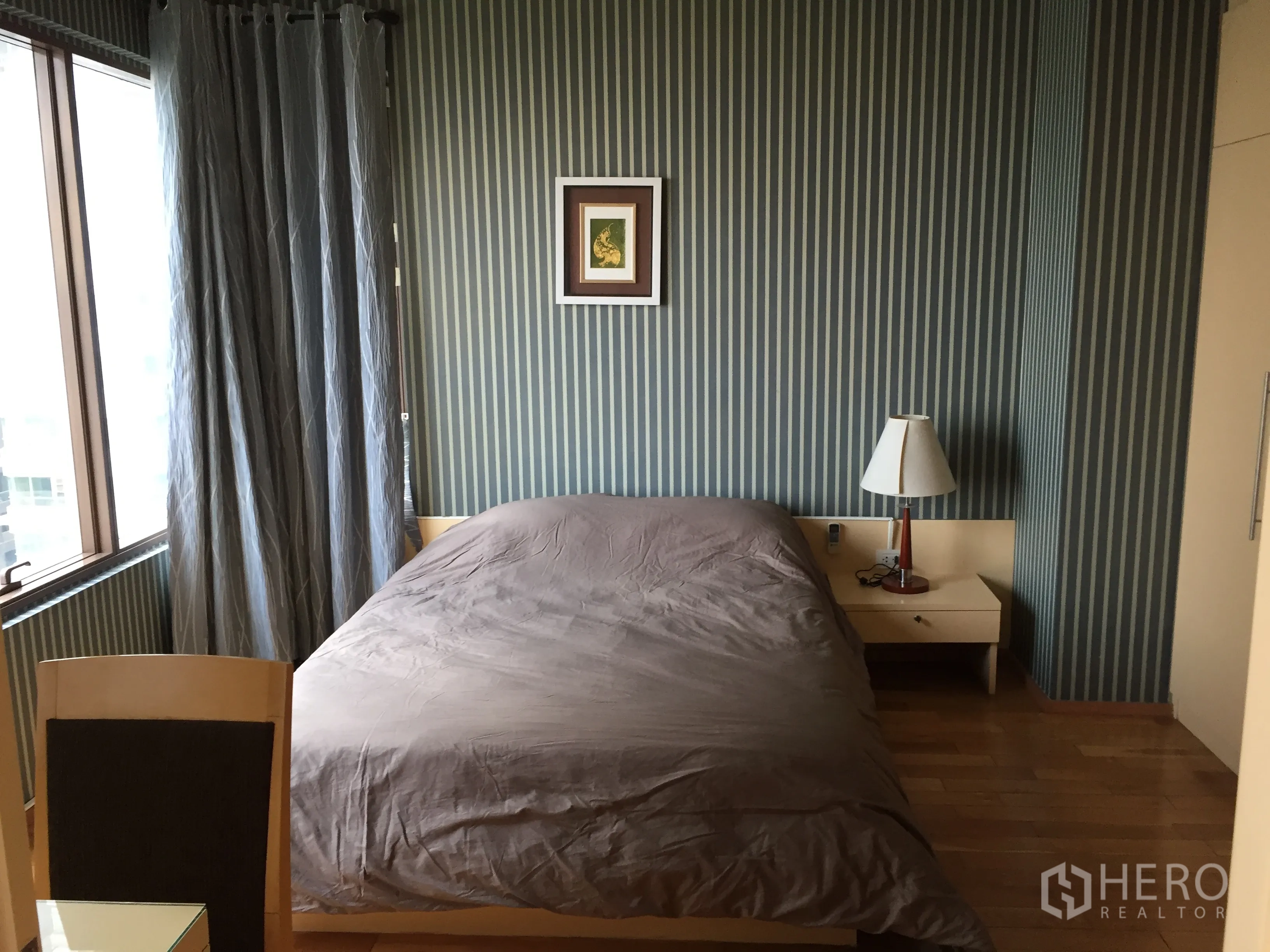 คอนโด ให้เช่าหรือขายในKhlong Toei, Bangkok - ห้องนอนอบอุ่นพร้อมเตียงคู่ โต๊ะข้างเตียง และกรอบรูปบนผนังลายทาง