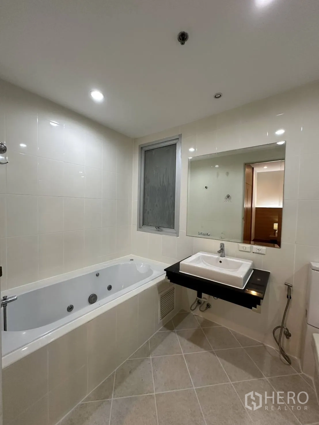 Condominium for rent in Watthana, Bangkok - Bright tiled bathroom with soaking bathtub, vanity, and toilet.