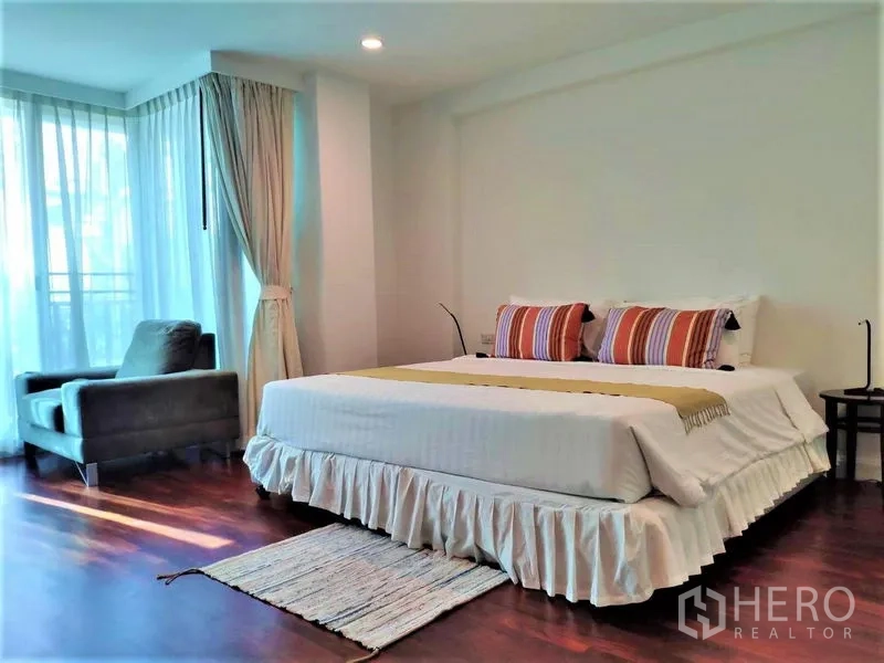 Condominium for rent in Bang Rak, Bangkok - Spacious master bedroom with a king bed, armchair, and wide windows.