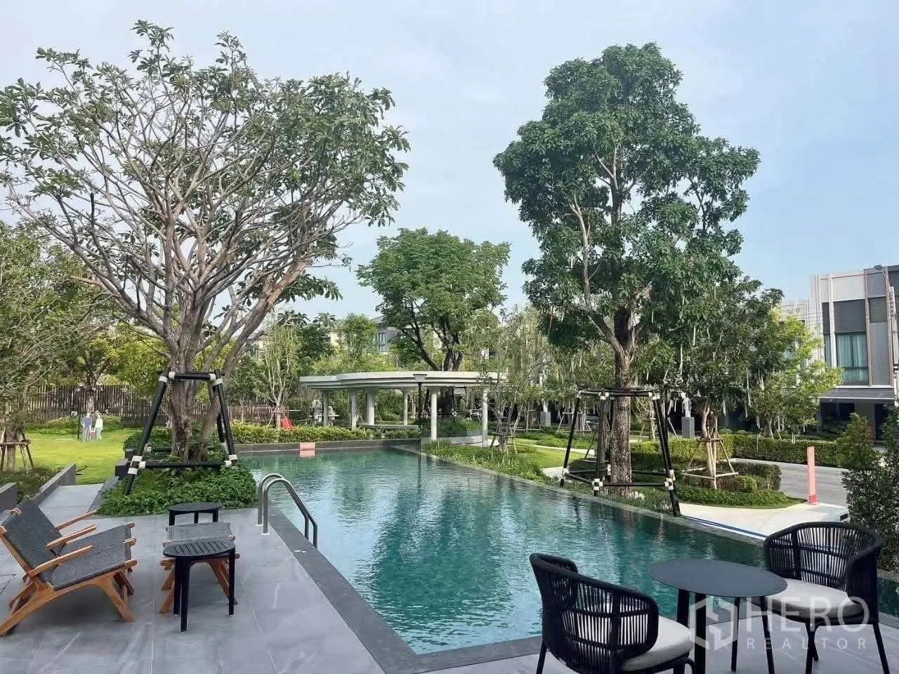 Townhouse for rent in Bang Phli, Samut Prakan - Outdoor swimming pool surrounded by trees and a seating deck.