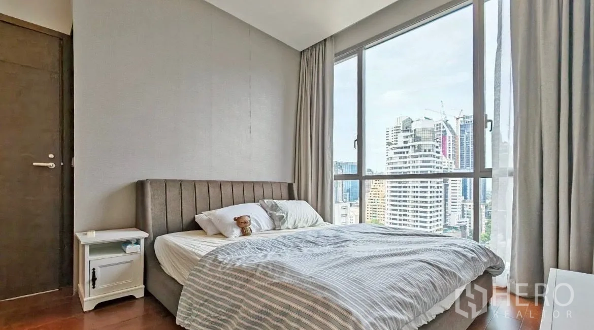 คอนโด ให้เช่าในWatthana, Bangkok - ห้องนอนพร้อมหน้าต่างบานใหญ่ เตียงหัวบุผ้า โต๊ะข้างเตียง และวิวสกายไลน์แบบพาโนรามา