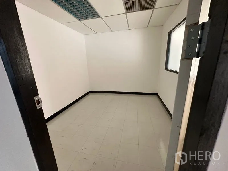 Office Space for rent in Ratchathewi, Bangkok - Compact private office with white walls, tiled floor, ceiling vent and internal window.