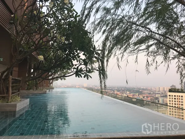 Condominium for rent in Watthana, Bangkok - Rooftop infinity pool with frangipani trees and panoramic Bangkok skyline.