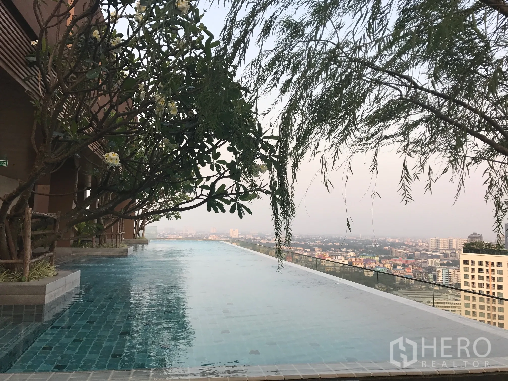 Condominium for rent in Watthana, Bangkok - Rooftop infinity pool with frangipani trees and panoramic Bangkok skyline.