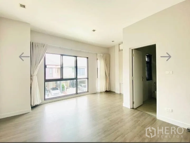 Detached House for sale in Saphan Sung, Bangkok - Sunny bedroom with wide window and door to an ensuite bathroom.