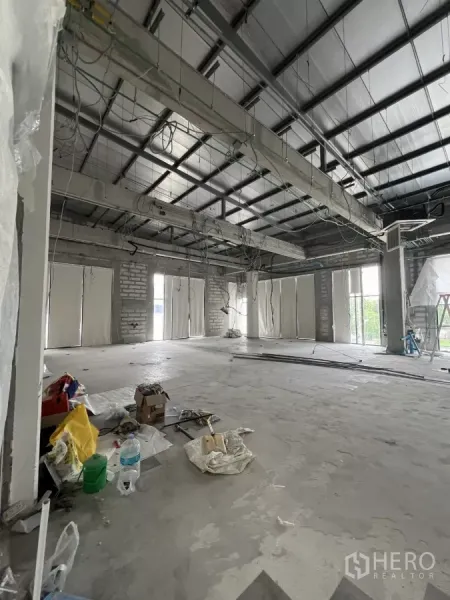 零售空间 出租在Khlong Toei, Bangkok - 未完成的店铺内部，裸露梁架与线路，多扇窗户，地面有施工材料。