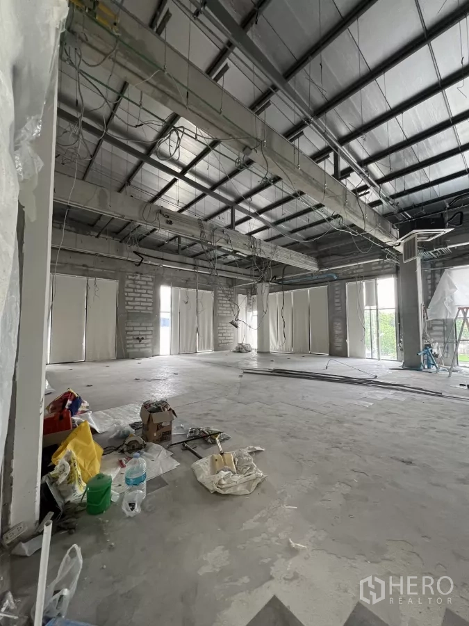 零售空间 出租在Khlong Toei, Bangkok - 未完成的店铺内部，裸露梁架与线路，多扇窗户，地面有施工材料。