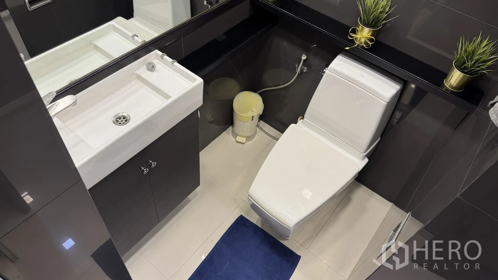 公寓 出租或出售在Khlong Toei, Bangkok - 紧凑卫浴，方形台盆、坐厕与黑色浴柜和大镜面。