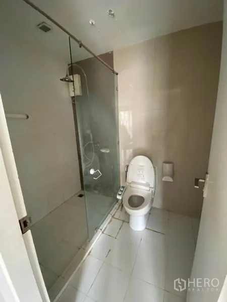 Condominium for rent in Watthana, Bangkok - Modern bathroom with glass-enclosed shower, toilet and light-toned tiles