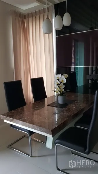 Condominium for rent in Ratchathewi, Bangkok - Dining area with marble table, black chairs and pendant lights next to sheer curtains.