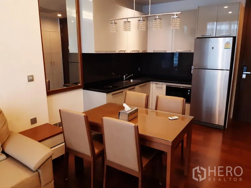 คอนโด ให้เช่าในWatthana, Bangkok - ครัวรูปตัวแอลพร้อมตู้ลอยเงางาม แบ็กสแปลชสีดำ โคมไฟแขวน โต๊ะทานอาหาร และตู้เย็นสแตนเลส