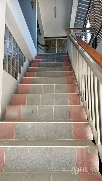 Retail Space for sale in Lam Luk Ka, Pathum Thani - Upward view of wide tiled stairs with wood-and-metal handrail.