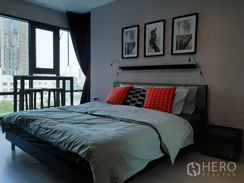 คอนโด ให้เช่าหรือขายในKhlong Toei, Bangkok - ห้องนอนพร้อมหน้าต่างบานใหญ่เห็นวิวเมือง เตียงปูผ้าพร้อมหมอนลวดลายสีสัน