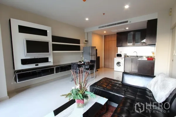 คอนโด ให้เช่าในWatthana, Bangkok - ห้องนั่งเล่นมีชุดชั้นวางทีวีบิลท์อิน โซฟาหนัง ติดกับครัวแบบโอเพ่นแปลน