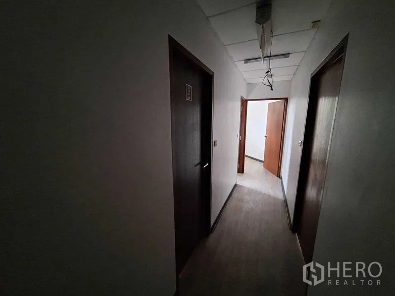Office Space for rent in Watthana, Bangkok - Dim hallway with several wooden doors leading to private rooms.