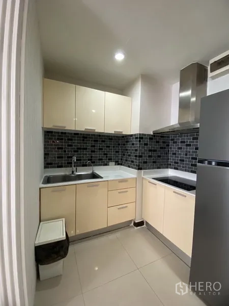 คอนโด ให้เช่าในWatthana, Bangkok - ครัวรูปตัวแอล ตู้บิวท์อินสีครีม แบ็กสแพลชกระเบื้องสีเข้ม เตา ฮูด และตู้เย็นสแตนเลส