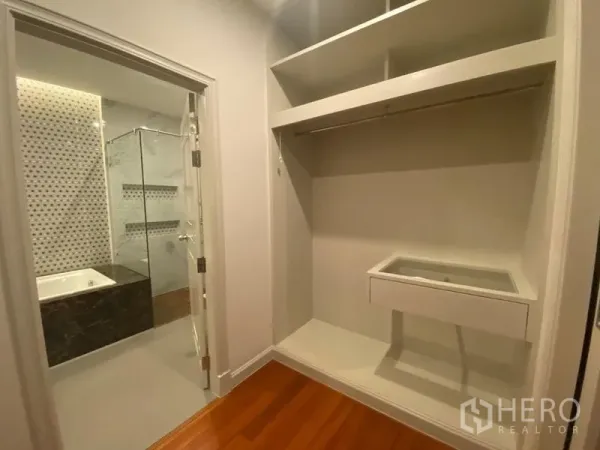 Condominium for rent in Bang Kapi, Bangkok - Walk-in closet leading to a bathroom with glass shower, bathtub and patterned mosaic wall tiles.