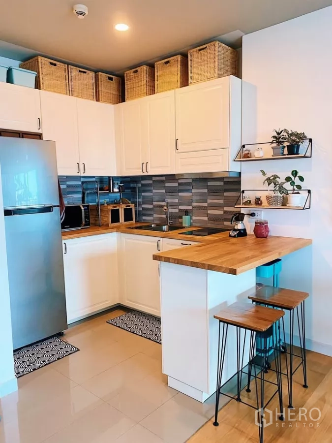 Condominium for rent in Watthana, Bangkok - Modern L-shaped kitchen with white cabinetry, wood countertops, breakfast bar and stools.