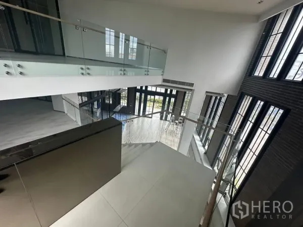 พื้นที่ขายปลีก ให้เช่าในBang Phli, Samut Prakan - มุมมองชั้นลอยของโถงโชว์รูมเพดานสูง พร้อมราวกระจกและหน้าต่างสูง