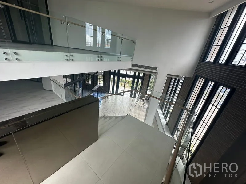 พื้นที่ขายปลีก ให้เช่าในBang Phli, Samut Prakan - มุมมองชั้นลอยของโถงโชว์รูมเพดานสูง พร้อมราวกระจกและหน้าต่างสูง