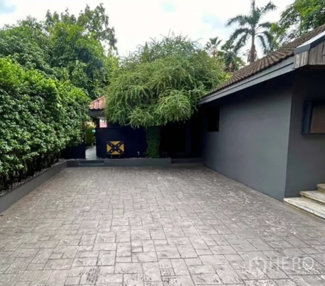 零售空间 出租在Yan Nawa, Bangkok - 铺装车道与入口庭院，周围绿树成荫。