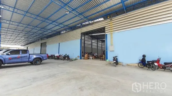 คลังสินค้า ให้เช่าในBang Kruai, Nonthaburi - อาคารโกดังสีฟ้าพร้อมประตูบานใหญ่ ลานโหลดมีหลังคา และพื้นที่จอดรถ