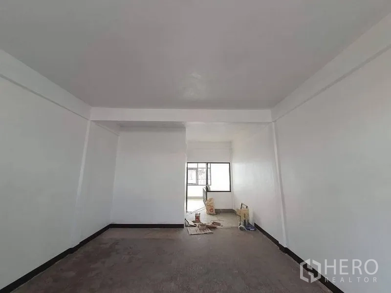 อาคารพาณิชย์ ให้เช่าในBangkok - ห้องอาคารพาณิชย์สว่าง ผนังสีขาว มีคานเพดานและหน้าต่างบานใหญ่ ปลายห้องมีวัสดุรีโนเวท