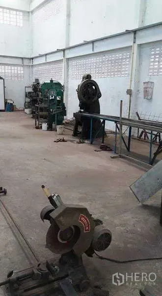 Warehouse for rent or sale in Nong Suea, Pathum Thani - Spacious workshop area with industrial machines and a cutting saw along the wall.