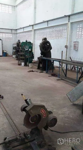 Warehouse for rent or sale in Nong Suea, Pathum Thani - Spacious workshop area with industrial machines and a cutting saw along the wall.