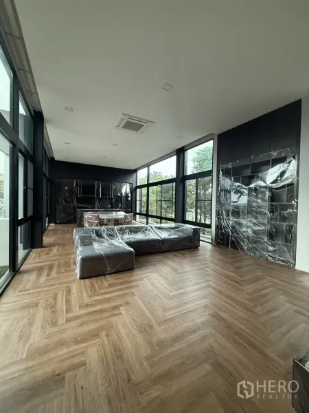 Detached House for rent in Saphan Sung, Bangkok - Spacious living room with herringbone wood floors, floor-to-ceiling windows and built-in cabinetry.